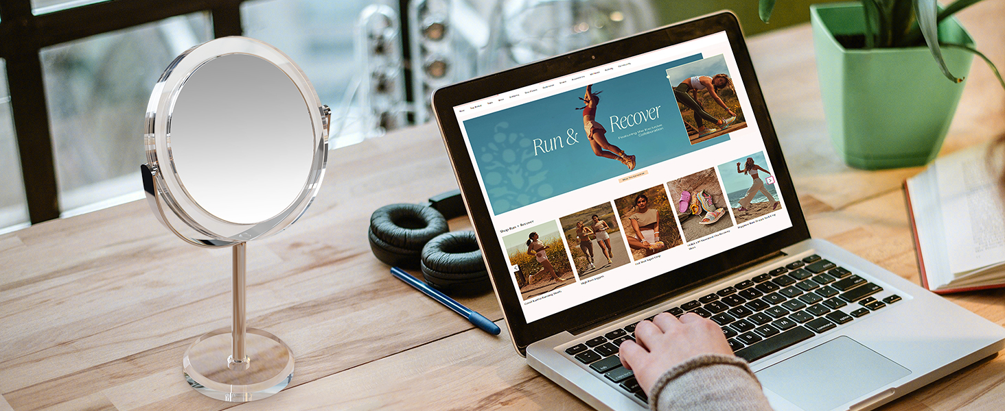 Desktop setup with circular vanity mirror and laptop displaying what appears to be an e-commerce or catalog website interface.
