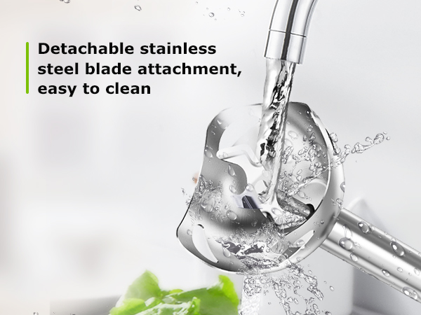 Close-up of detachable stainless steel blade attachment being cleaned under running water, with green leaf visible in corner.