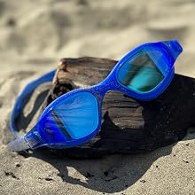 Blue Mirror finish goggles on driftwood on a sandy beach