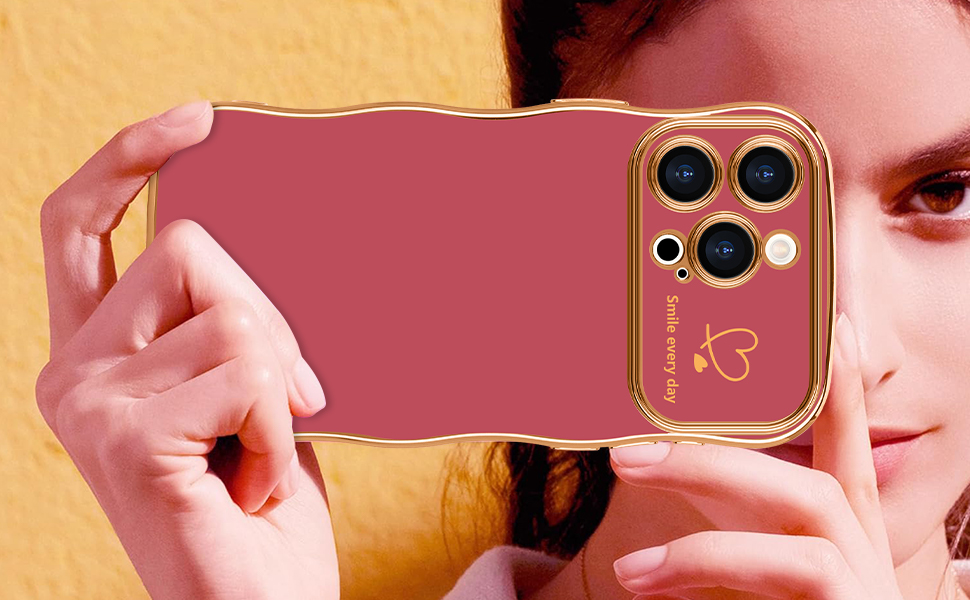Pink smartphone case with gold trim and triple camera cutout design, featuring a decorative heart detail.