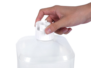 Hand pressing down on a white pump dispenser attached to a large, clear plastic bottle or container. The bottle appears to contain a liquid product.