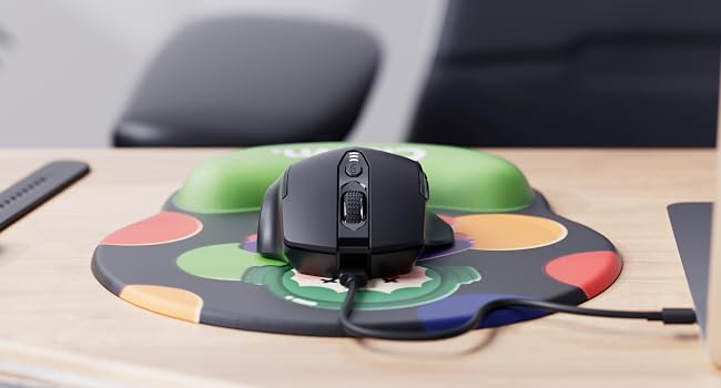 Black computer mouse on a colorful circular mousepad with geometric patterns. The mousepad has green, red, and yellow sections visible on a desk.