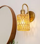 Circular brown-framed mirror with gold wall sconces featuring textured glass shades, emitting warm light. Modern bathroom decor elements visible.