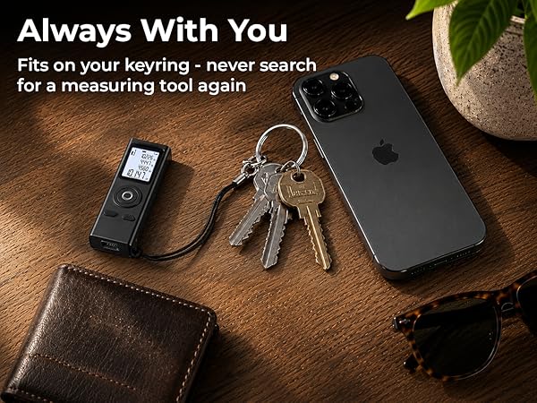 Pocket laser measuring tool clipped to keys beside a phone, replaces a bulky measuring tape