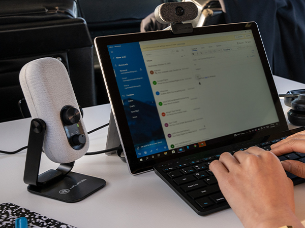 Go talk mic on a white table next to a tablet and person typing on a keyboard