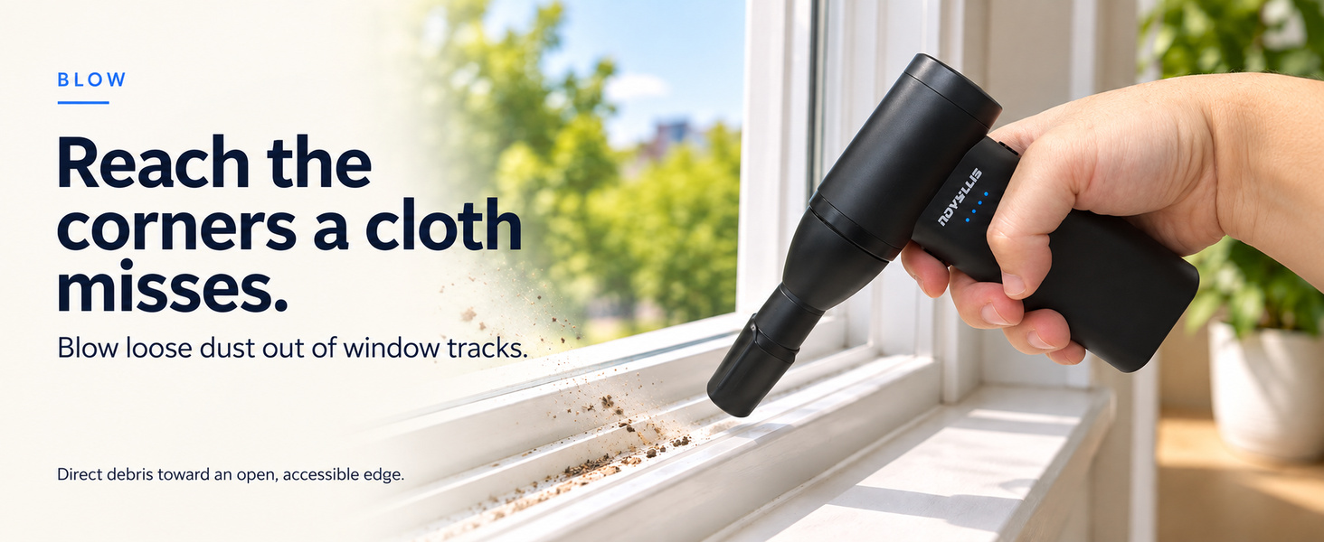 Handheld air blower clearing loose dust from window tracks with a focused nozzle