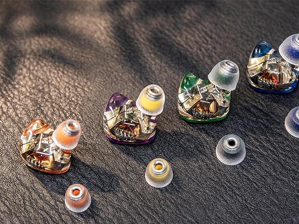 Collection of decorative glass or crystal objects arranged on a textured sand or beige surface, photographed under natural lighting conditions.