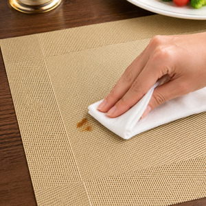 Champagne gold woven placemat being wiped after a small dining splash