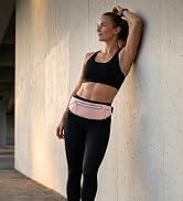 Woman placing a smartphone in the front zippered pocket of a pink running belt.