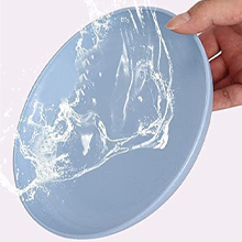 Hand holding a light blue circular plate or dish with a white water splash pattern on its surface.