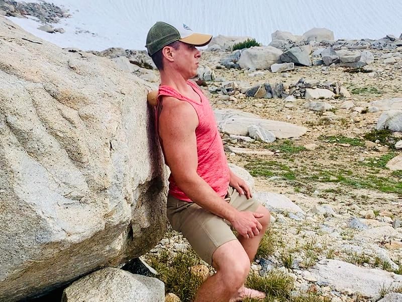 Man rolling out his back on a boulder with a rawlogy cork massage ball