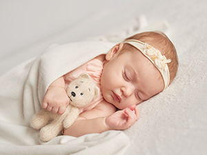 newborn baby girl sleeping with a teddy bear