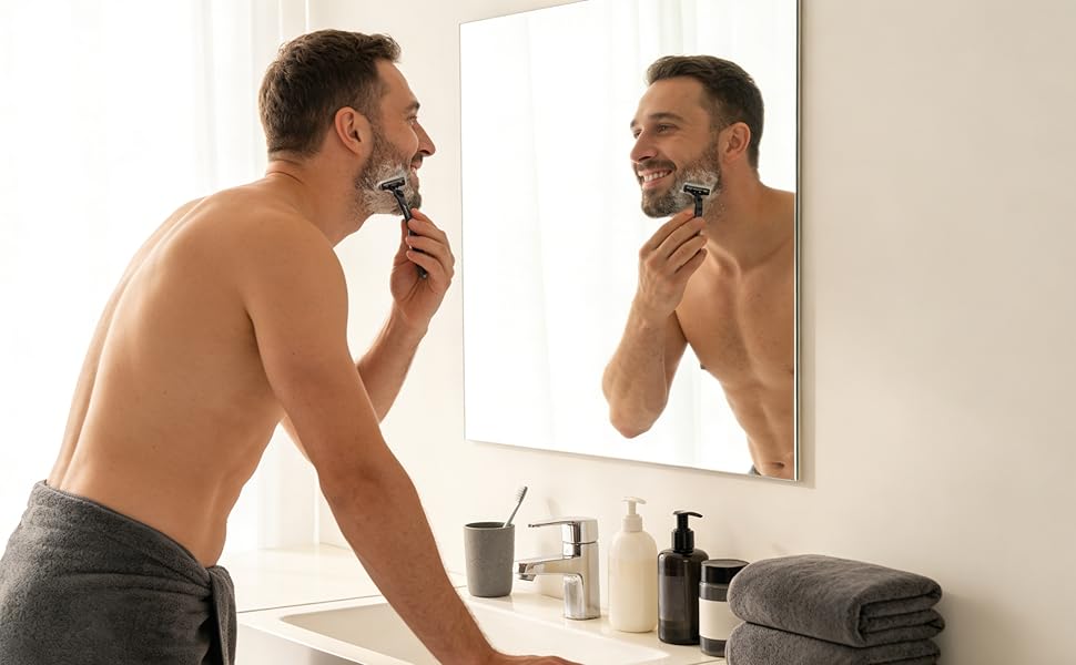Person at bathroom sink with mirror reflection, grooming routine scene with dark towels and personal care products visible on counter.