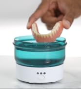 Person holding denture over ultrasonic cleaner device