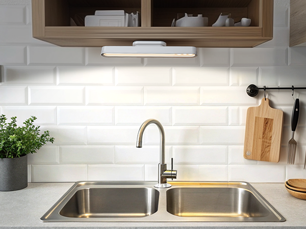 a kitchen sink with a light under the sink.