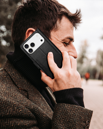 Person in profile holding smartphone with white protective case near ear, demonstrating phone usage outdoors.