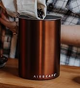person in a plaid shirt pouring coffee beans into an airscape coffee storage canister