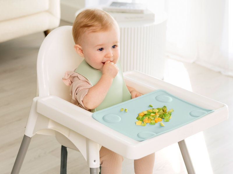 Baby eating in high chair with Prep silicone placemat keeping food organized during mealtime