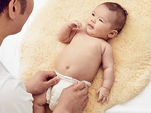 A dad changing a baby wearing an Esembly Inner