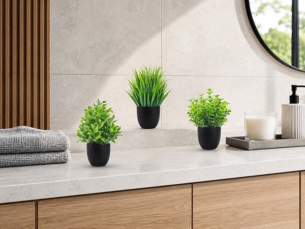 three artificial green plants black pots bathroom vanity decor