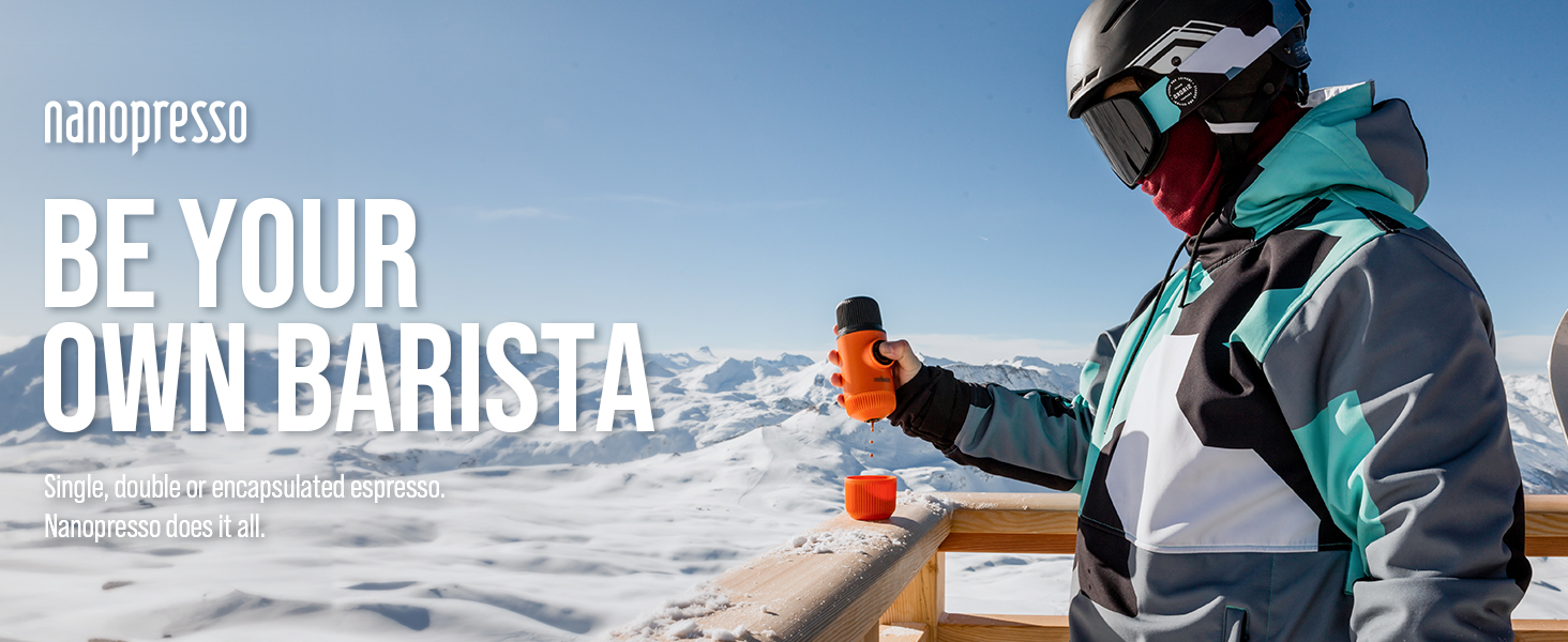 Nanopresso portable coffee maker being used outdoors in snowy mountain setting by person in winter sports gear.