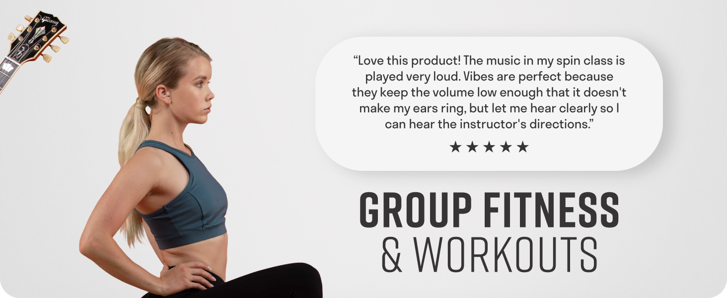 Woman working out in group fitness class wearing clear earplugs to tolerate loud noises in workout
