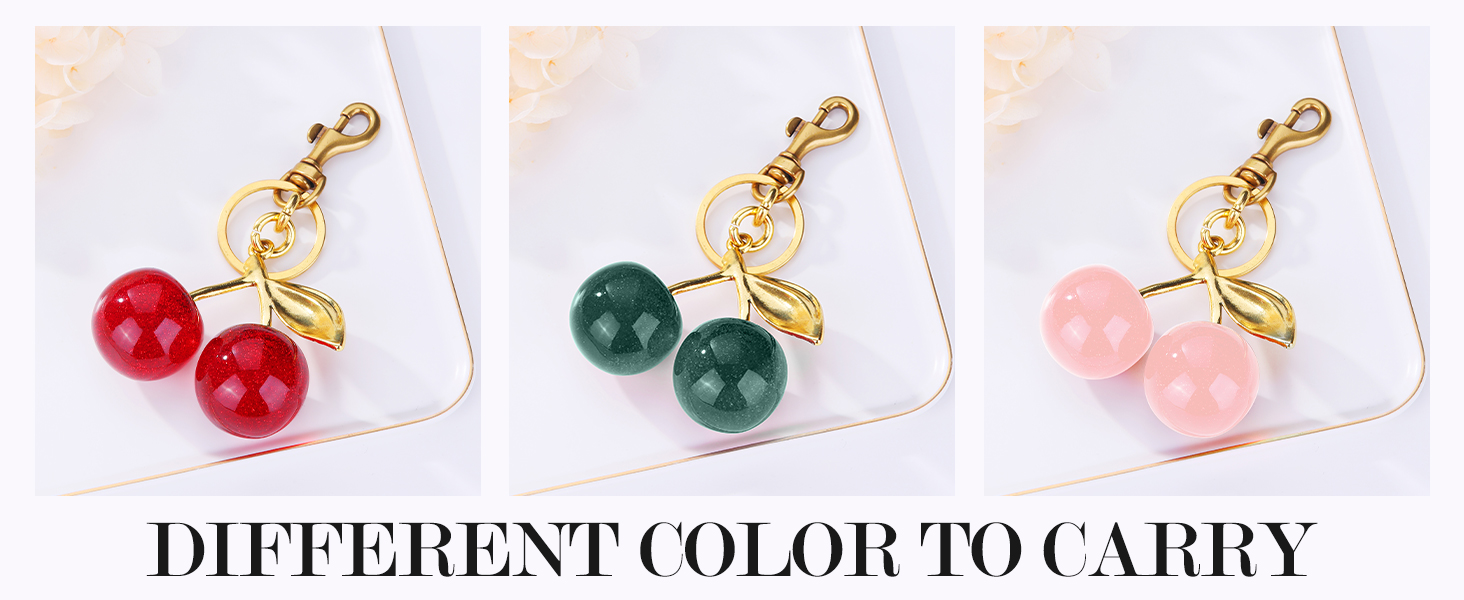 Three cherry-shaped charms in red, green, and pink colors, each attached to a gold-toned clasp. Text reads 'DIFFERENT COLOR TO CARRY'.