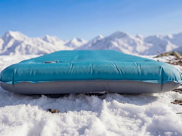 Airlive2000 sleeping pad on snow with mountain backdrop.