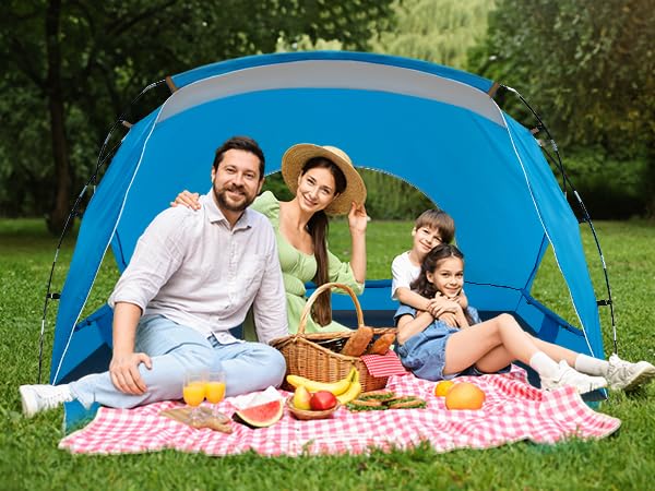 Family of four sitting in tent camping on the grass