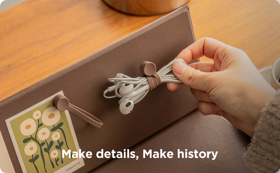 Text reads 'Make details, Make history'. Overhead shot of hands holding a curved metal component over a wooden workstation with technical diagrams and components visible.