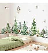Children's bedroom with watercolor-style forest wall mural featuring pine trees, birds, and woodland elements. Green bedding and natural wooden toys visible.