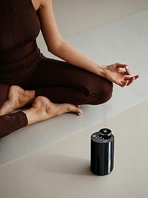A young lady is doing yoga in the living room, with an aromatherapy machine placed beside her.