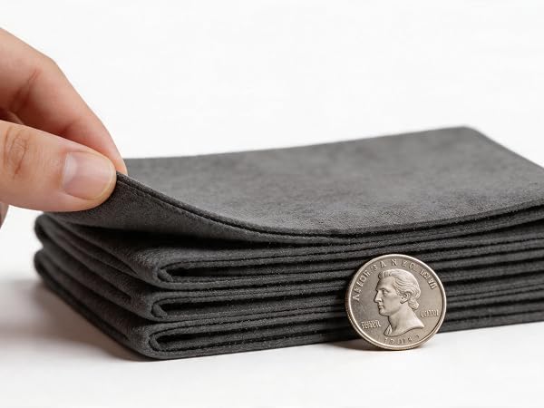 Fingers pinching edge of thick grey microfiber cloth showing density.