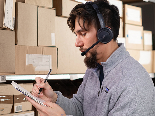 Multiple images showing a person wearing headphones in what appears to be a warehouse or office setting, working with documents.