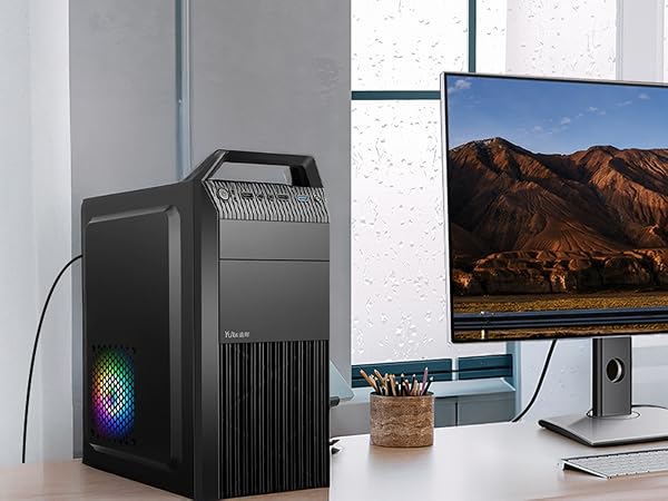 Desktop computer setup with a black tower case featuring RGB lighting and ventilation, connected to a large monitor displaying a mountain landscape.