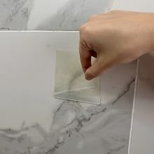 Hand peeling top HairStixies sheet off of pad attached to shower wall