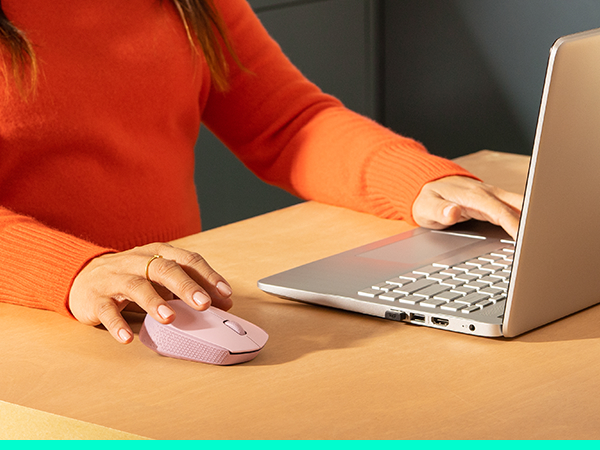 a woman working on a laptop using m170 wireless rose mouse
