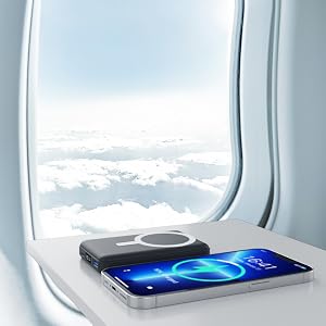 Smartphone with glowing blue display screen positioned on airplane window seat, with cloud landscape visible through airplane window behind.