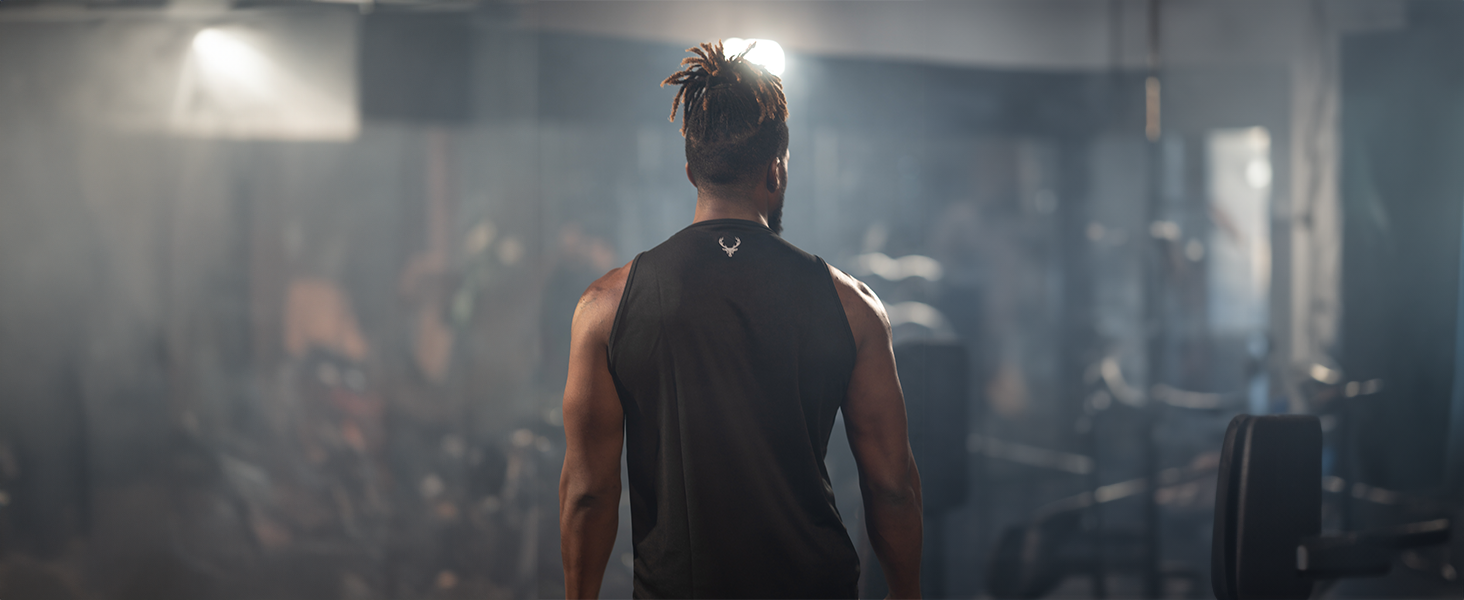 Man wearing Bucked Up tank top facing away from the camera in a gym