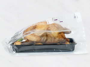 A roasted chicken in a plastic bag in a tray