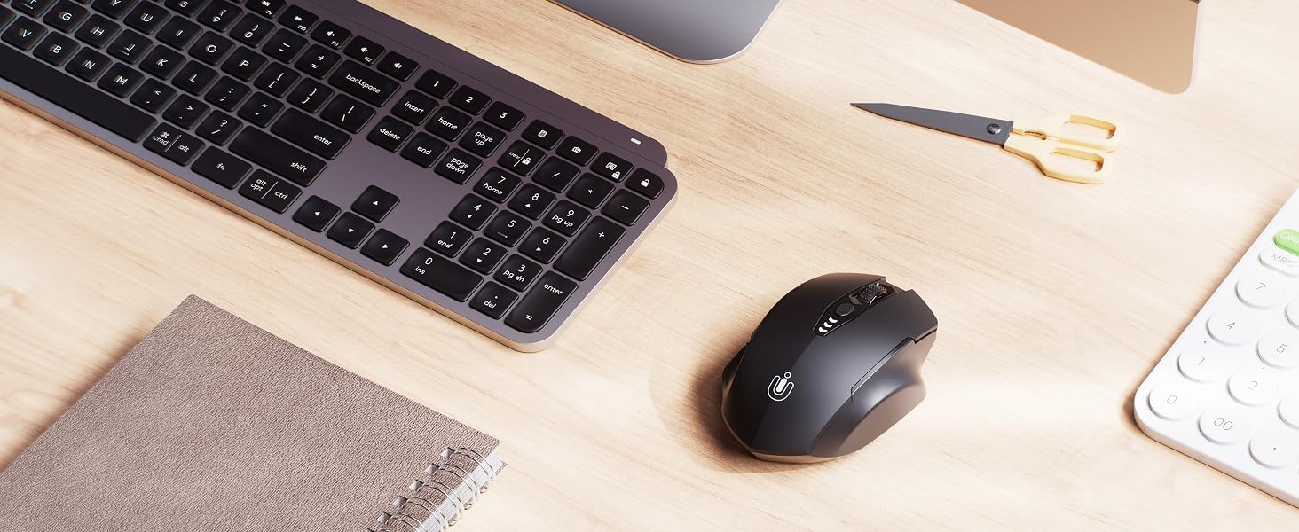 Desktop workspace with wireless keyboard, mouse, and calculator on light wooden surface.