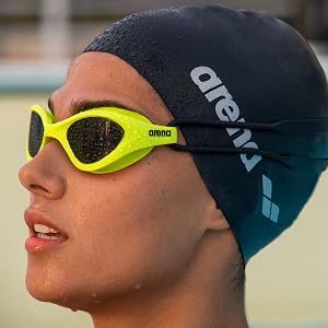close-up of woman wearing a black arena swim cap and neon yellow arena swim goggles in the summer