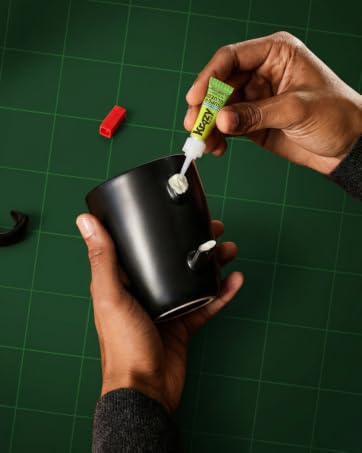 Hands using Krazy Glue Super Glue to repair broken black ceramic mug handle with strong fast bond