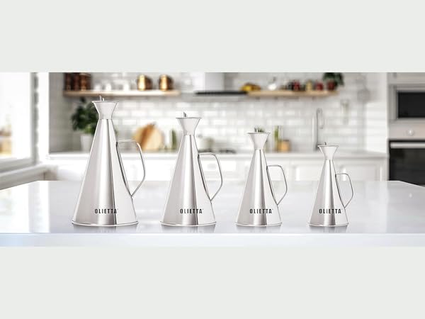 Four stainless steel conical pourers of increasing sizes arranged in a row on a white kitchen countertop.