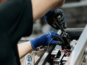 Blue work gloves used by electrician repairing an industrial electrical control panel.