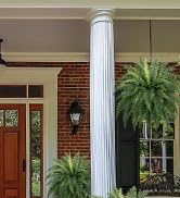 White decorative column on a brick building exterior, with green potted palm plants flanking the entrance.
