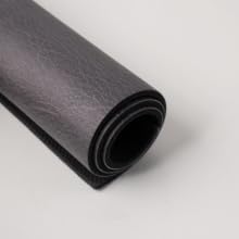 Rolled black PU leather coffee mat showing flexible, cushioned, non-slip design.