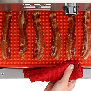 bacon cooking in toaster oven using raised mat to catch all drippings