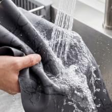 Black marble coffee mat rinsed under faucet, showing waterproof easy-clean surface.