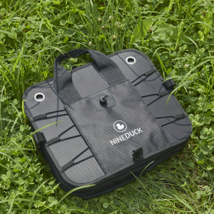 Folded black NINEDUCK trunk organizer with handles, shown outdoors on grass.